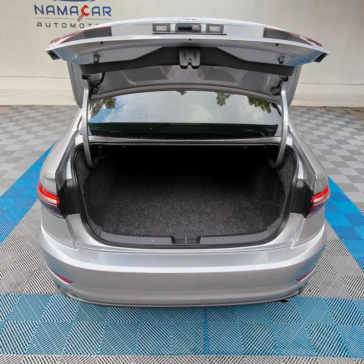 Vista exterior trasera de la cajuela abierta que muestra el amplio espacio del portaeconómico tapizado en alfombra oscura de un auto sedán deportivo Volkswagen Jetta 2.0 GLI DSG automático año 2021 seminuevo en color gris plata, en Namacar Automotriz.