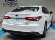 Auto sedán híbrido Toyota Camry 2.5 HEV XLE año 2024 seminuevo en color blanco, vista exterior trasera en ángulo de tres cuartos derecha exhibido en Namacar Automotriz.