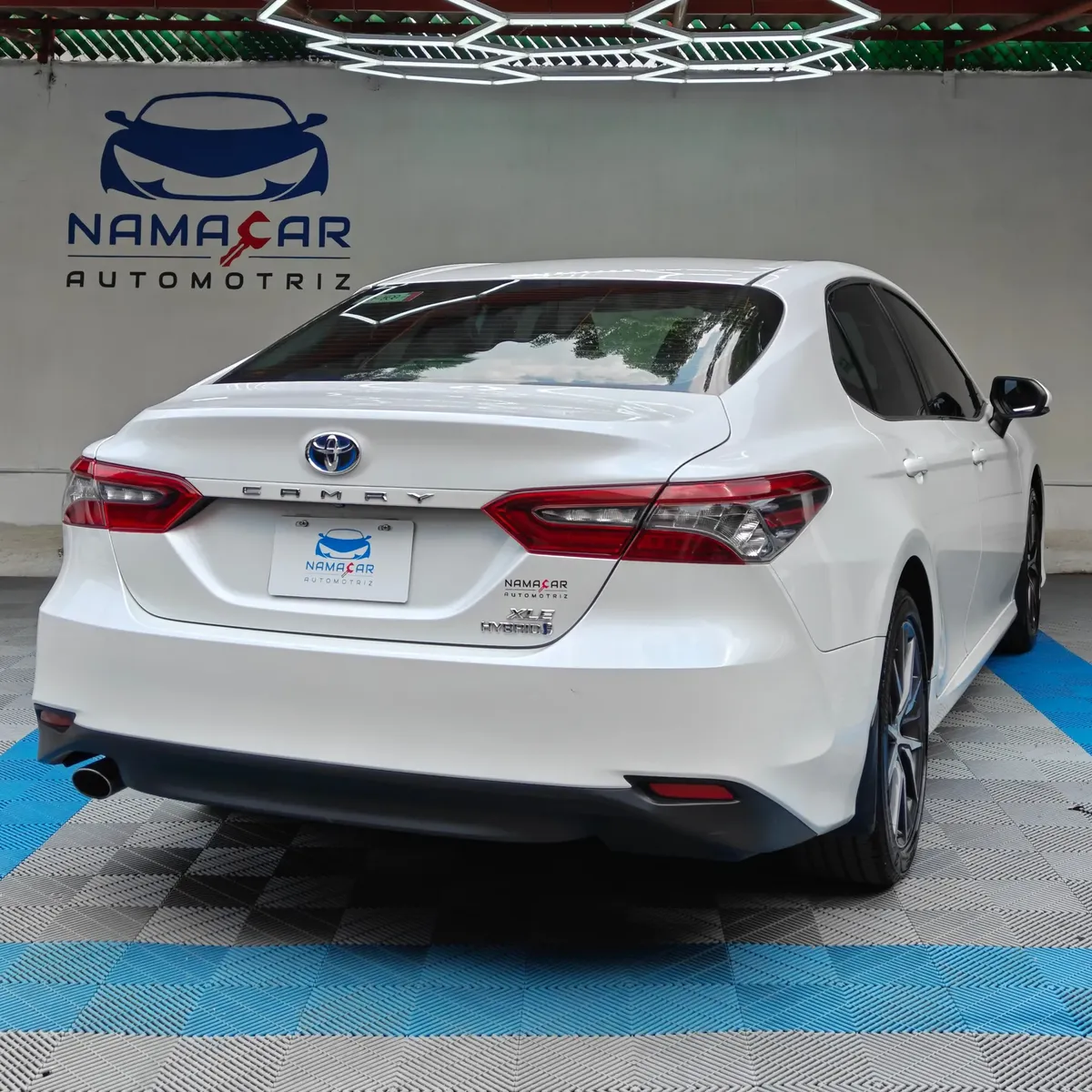 Auto sedán híbrido Toyota Camry 2.5 HEV XLE año 2024 seminuevo en color blanco, vista exterior trasera en ángulo de tres cuartos derecha exhibido en Namacar Automotriz.