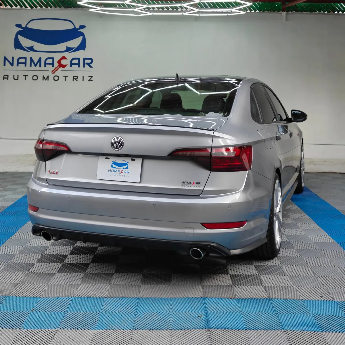 Auto sedán deportivo Volkswagen Jetta 2.0 GLI DSG automático año 2021 seminuevo en color gris plata, vista exterior trasera en ángulo de tres cuartos derecha exhibido en Namacar Automotriz.