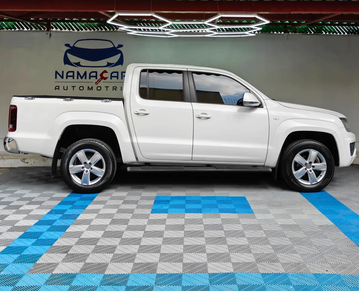 Camioneta pickup Volkswagen Amarok 2.0 Highline 4Motion automática año 2018 seminueva en color blanco, vista exterior de perfil lateral derecho completo exhibida en Namacar Automotriz.