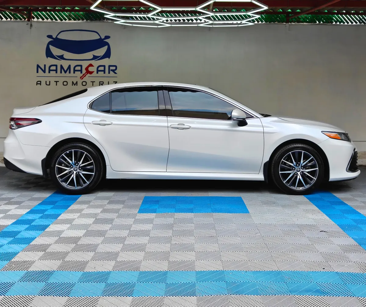 Auto sedán híbrido Toyota Camry 2.5 HEV XLE año 2024 seminuevo en color blanco, vista exterior de perfil lateral derecho completo exhibido en Namacar Automotriz.