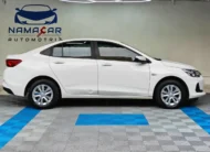 Auto sedán Chevrolet Onix 1.3 LS manual año 2024 seminuevo en color blanco, vista exterior lateral perfil derecho completo exhibido en Namacar Automotriz.