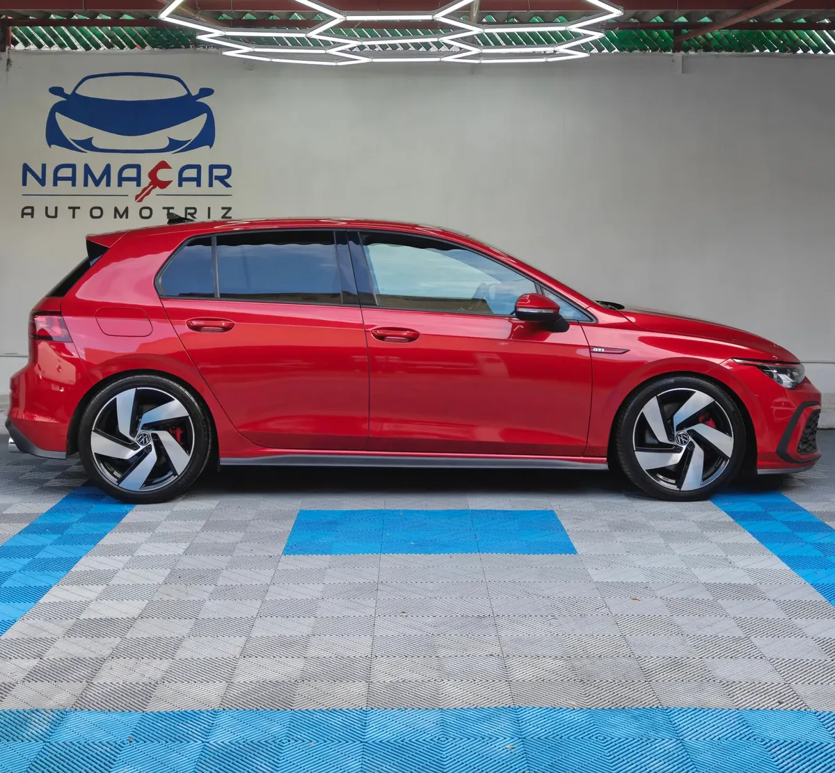 Hatchback deportivo Volkswagen Golf GTI 2.0 L de 241 HP automático DSG7 año 2024 seminuevo en color rojo brillante, vista exterior lateral perfil derecho completo exhibido en Namacar Automotriz.