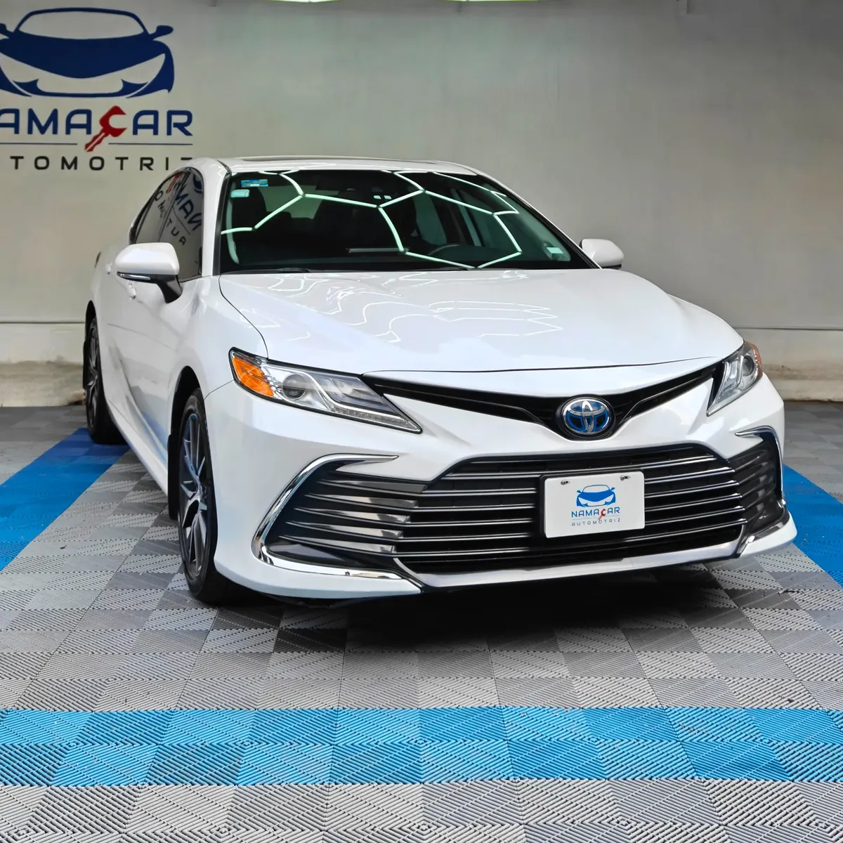 Auto sedán híbrido Toyota Camry 2.5 HEV XLE año 2024 seminuevo en color blanco, vista exterior frontal en ángulo de tres cuartos derecha exhibido en Namacar Automotriz.
