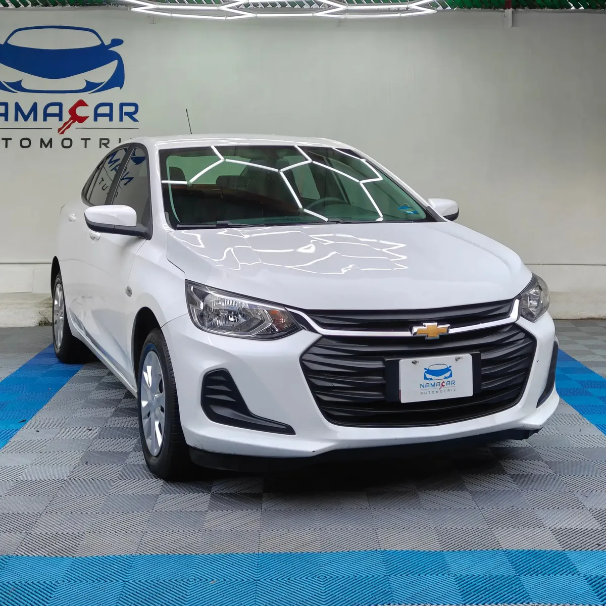 Auto sedán subcompacto Chevrolet Onix 1.3 LS manual año 2024 seminuevo en color blanco, vista exterior frontal en ángulo de tres cuartos derecha exhibido en Namacar Automotriz.