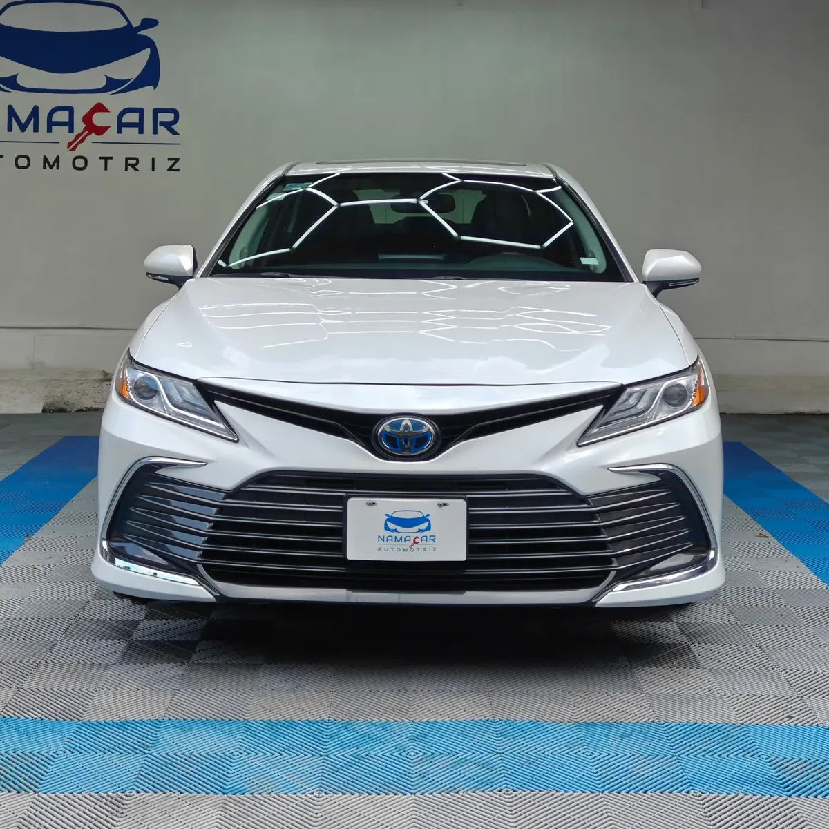 Auto sedán híbrido Toyota Camry 2.5 HEV XLE año 2024 seminuevo en color blanco, vista exterior frontal directa y centrada exhibido en Namacar Automotriz.